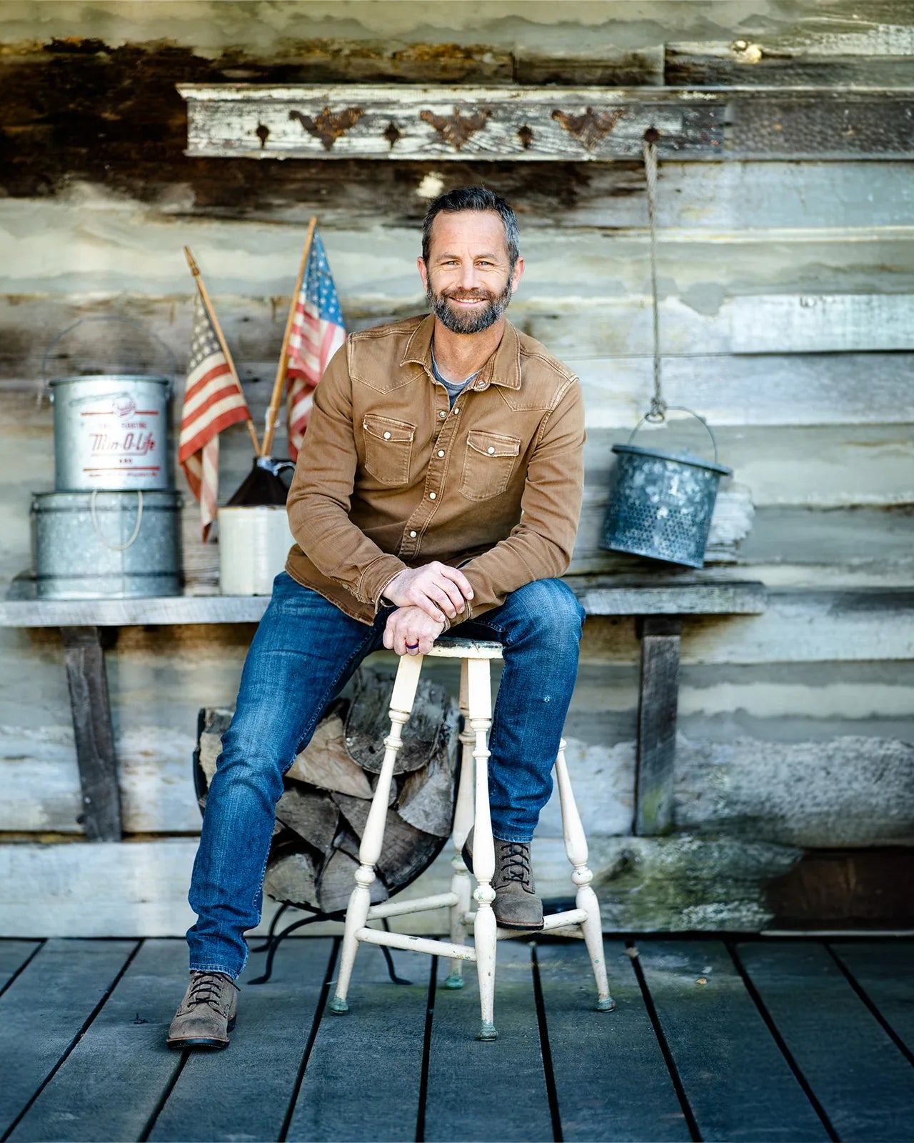 Kirk Cameron seated in front of a weathered timber wall
